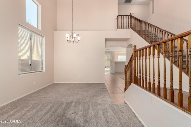 staircase with an inviting chandelier, a towering ceiling, and carpet floors