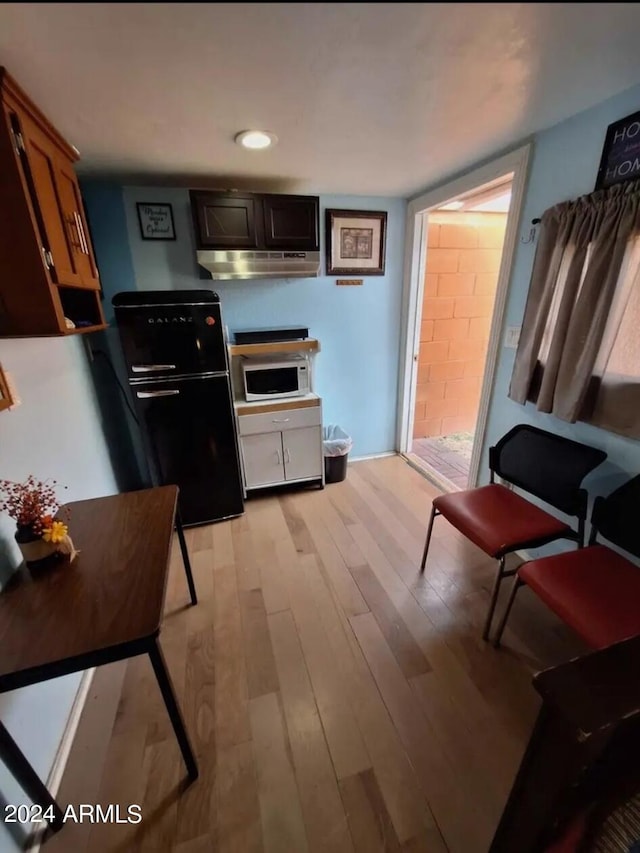 kitchen with light hardwood / wood-style flooring and black fridge