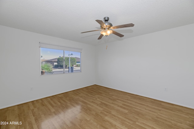 spare room featuring ceiling fan, light hardwood / wood-style flooring, and a textured ceiling