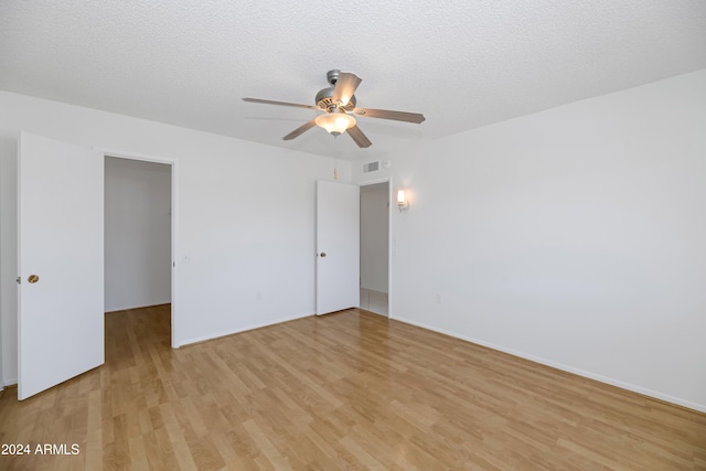 spare room with ceiling fan, light wood-type flooring, and a textured ceiling