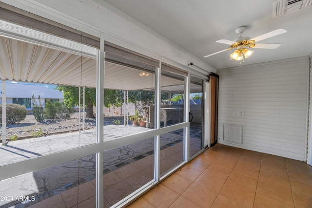 unfurnished sunroom featuring ceiling fan