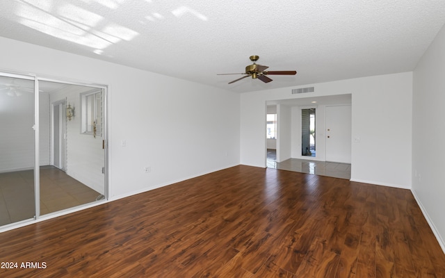 spare room with a textured ceiling, ceiling fan, and dark hardwood / wood-style floors