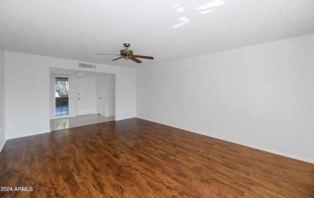 unfurnished room with a textured ceiling, ceiling fan, and dark wood-type flooring