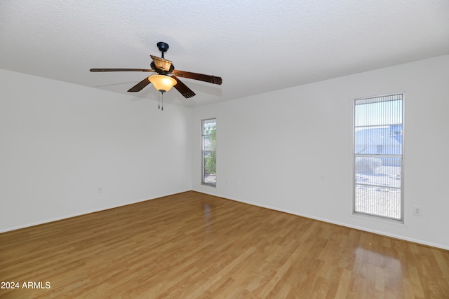 spare room featuring ceiling fan, light hardwood / wood-style flooring, and a textured ceiling