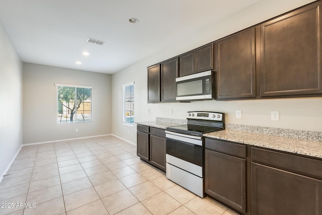 kitchen with light tile patterned floors, light stone counters, stainless steel appliances, and dark brown cabinetry