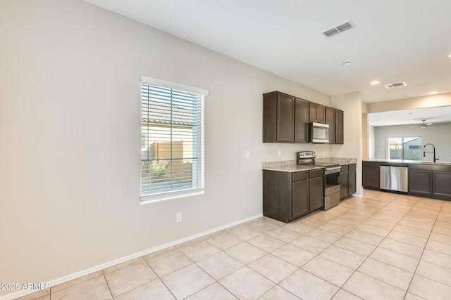 kitchen featuring light tile patterned flooring, appliances with stainless steel finishes, sink, and dark brown cabinets