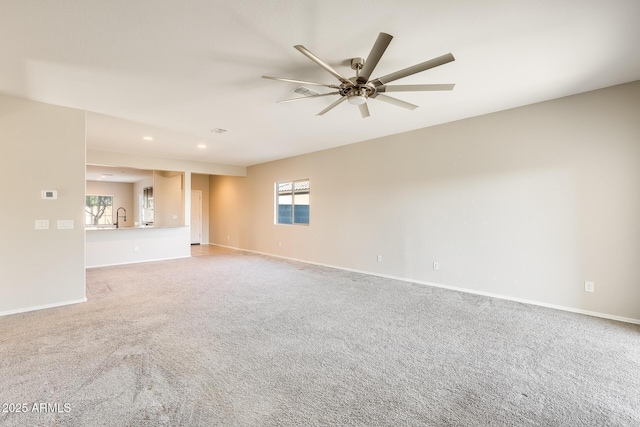 carpeted spare room with ceiling fan, a wealth of natural light, and sink