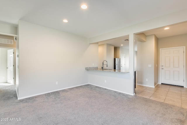 unfurnished living room with light carpet and sink