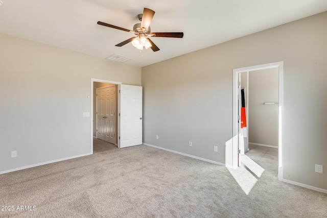 unfurnished bedroom with ceiling fan, light colored carpet, and a walk in closet