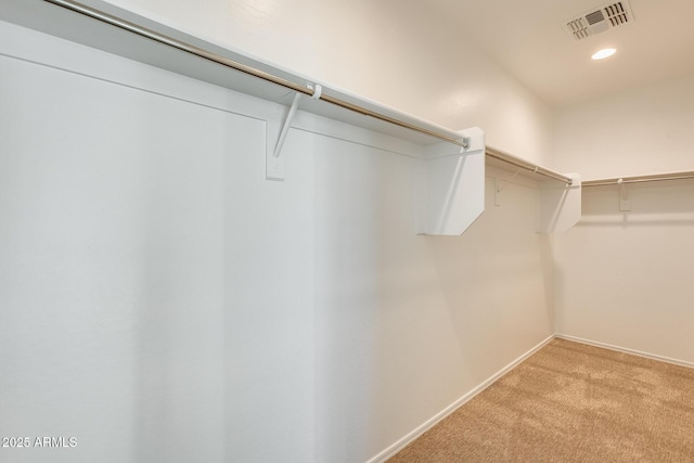 walk in closet with light colored carpet