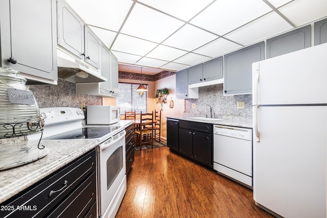 kitchen with dark wood-style flooring, a sink, white appliances, a drop ceiling, and under cabinet range hood