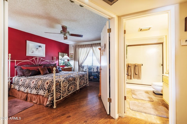 bedroom with visible vents, connected bathroom, a textured ceiling, wood finished floors, and baseboards