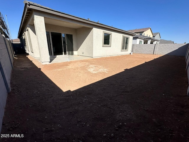 back of property with a fenced backyard and stucco siding