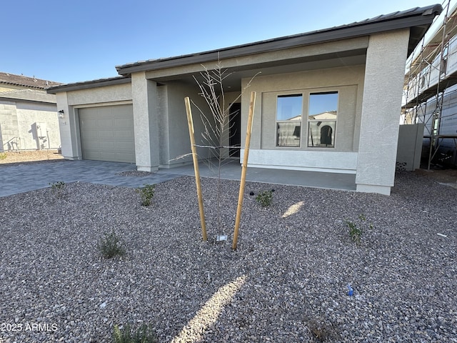 view of front of home featuring a garage, decorative driveway, and stucco siding