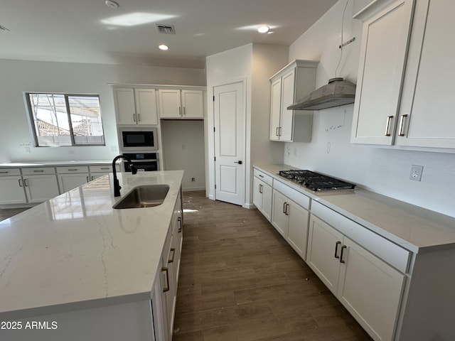 kitchen with visible vents, dark wood-style flooring, light stone countertops, stainless steel appliances, and a sink