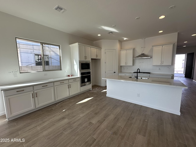 kitchen with dark wood finished floors, visible vents, appliances with stainless steel finishes, white cabinetry, and a sink