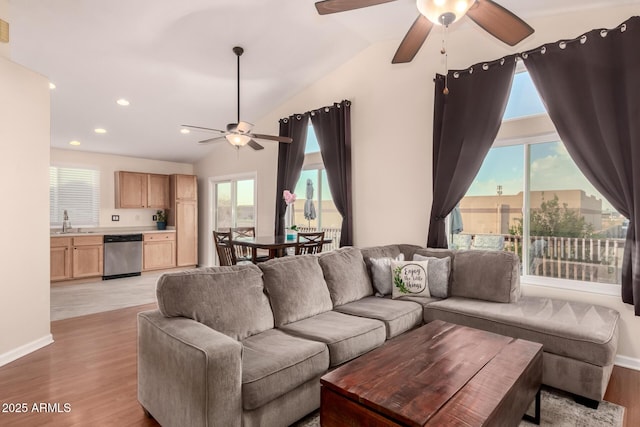 living area featuring lofted ceiling, light wood-style flooring, ceiling fan, and a wealth of natural light