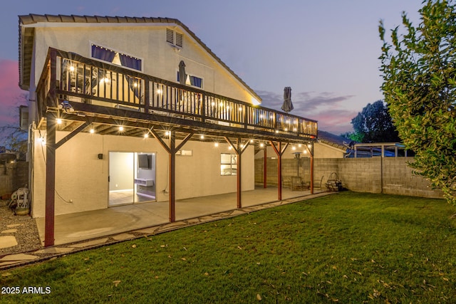 back of house with a deck, fence, a yard, stucco siding, and a patio area