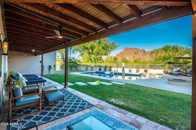 view of patio featuring a fenced in pool, ceiling fan, a fire pit, and a mountain view