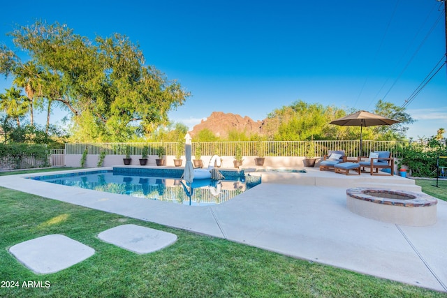 view of swimming pool featuring a mountain view, a lawn, an outdoor fire pit, and a patio