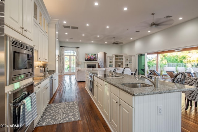 kitchen featuring light stone counters, appliances with stainless steel finishes, dark hardwood / wood-style flooring, sink, and white cabinets