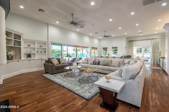 living room with a wealth of natural light, ceiling fan, a high ceiling, and dark hardwood / wood-style flooring