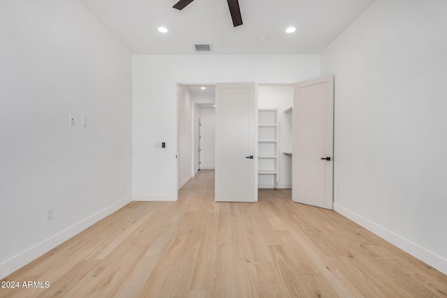 unfurnished bedroom featuring a spacious closet, a closet, ceiling fan, and light hardwood / wood-style floors