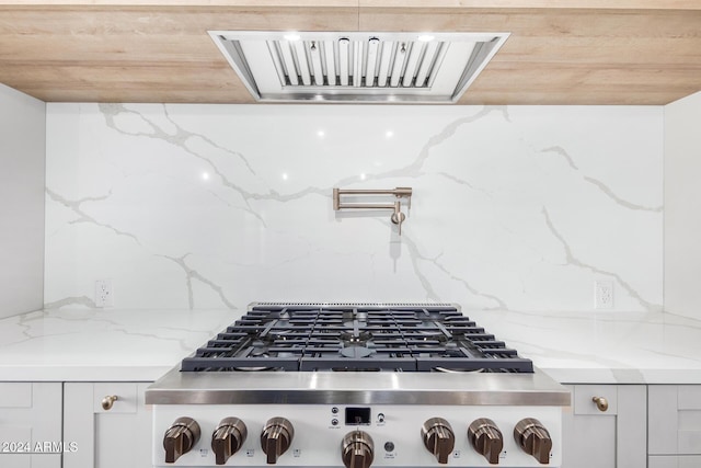 interior details with light stone counters, backsplash, and stainless steel gas cooktop