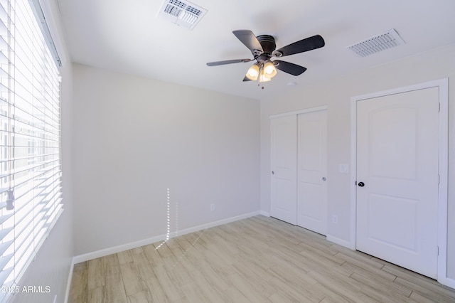 unfurnished bedroom featuring baseboards, a closet, visible vents, and light wood-style floors