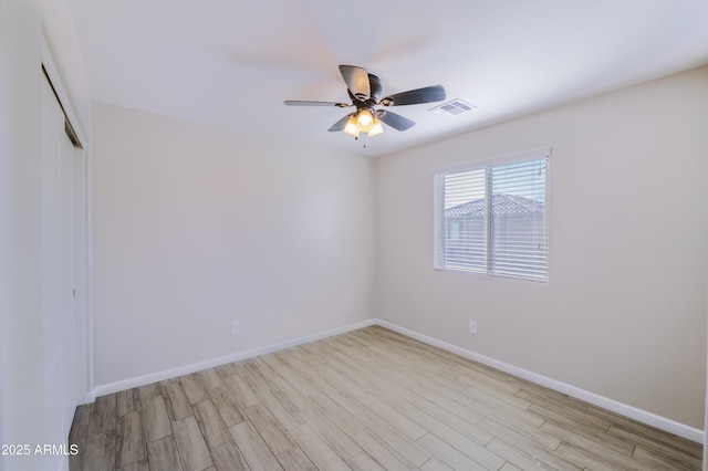 unfurnished room featuring a ceiling fan, visible vents, baseboards, and wood finished floors