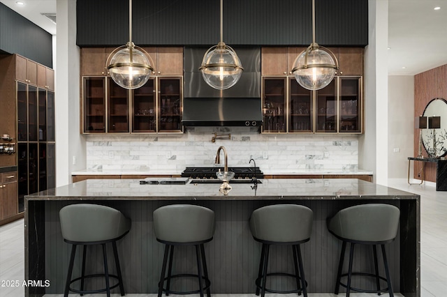 kitchen featuring a kitchen island with sink, dark stone countertops, and a kitchen bar