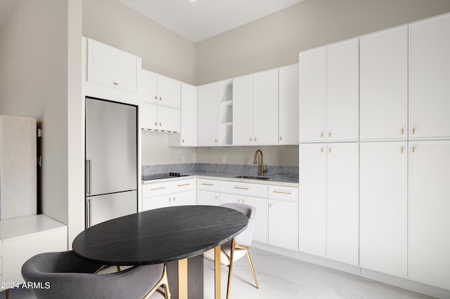 kitchen with stainless steel built in refrigerator, sink, and white cabinets