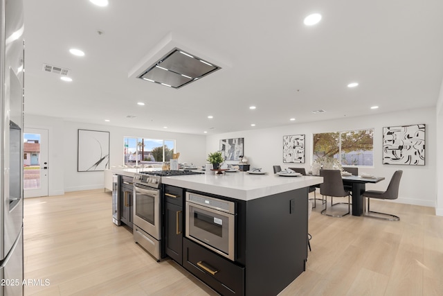 kitchen with gas range, a center island, a breakfast bar area, and light wood-type flooring