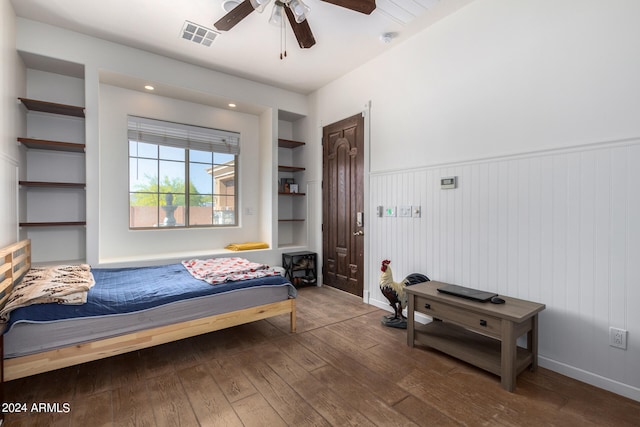 bedroom featuring ceiling fan, hardwood / wood-style flooring, and wooden walls