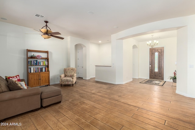 living room with ceiling fan with notable chandelier and light hardwood / wood-style flooring