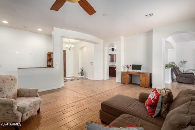 living room featuring ceiling fan with notable chandelier and light hardwood / wood-style floors