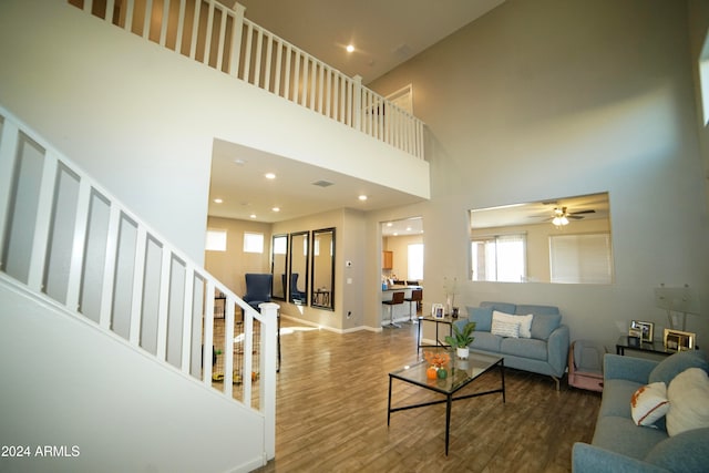 living room with ceiling fan, hardwood / wood-style floors, and a towering ceiling