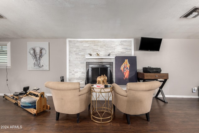 living room with a textured ceiling, dark wood-type flooring, and a fireplace