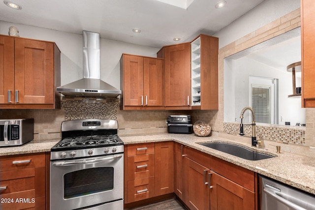 kitchen featuring wall chimney range hood, appliances with stainless steel finishes, sink, and decorative backsplash