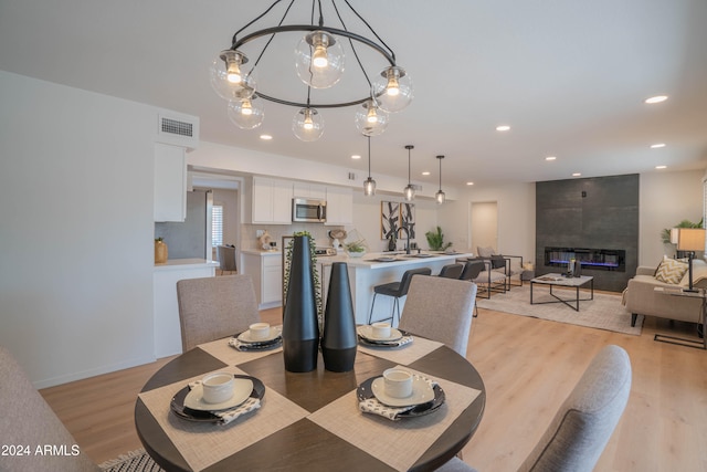 dining room featuring light hardwood / wood-style flooring, sink, an inviting chandelier, and a fireplace