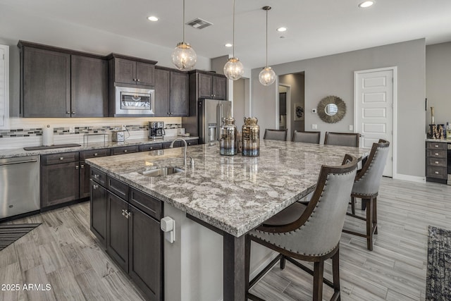 kitchen featuring pendant lighting, backsplash, a kitchen breakfast bar, a spacious island, and appliances with stainless steel finishes