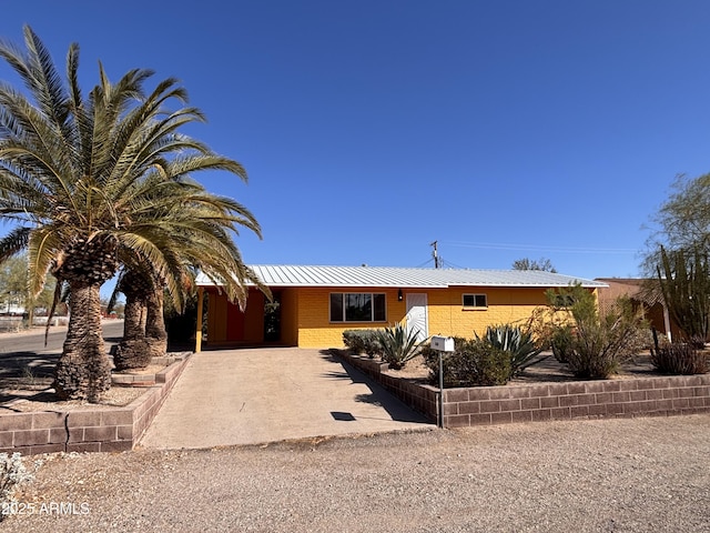 single story home featuring an attached carport, concrete driveway, and metal roof