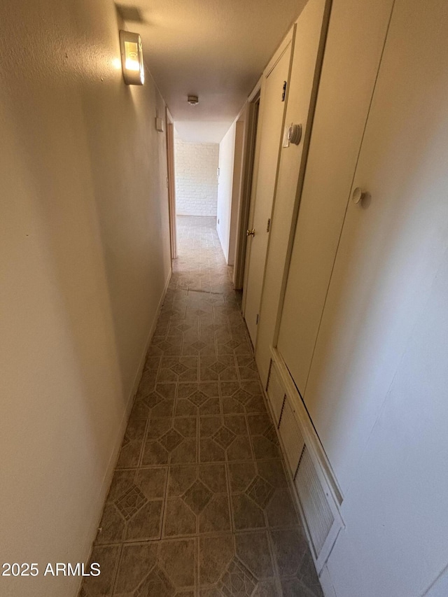 hallway with tile patterned flooring, visible vents, and baseboards