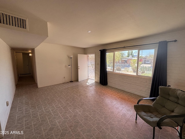 sitting room with visible vents and brick wall