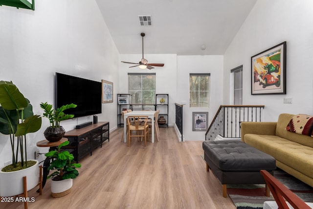 living room with ceiling fan, lofted ceiling, and light wood-type flooring