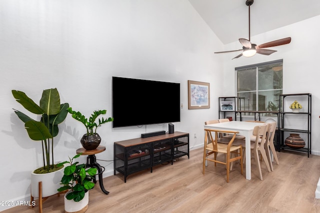 dining space featuring high vaulted ceiling, ceiling fan, and light wood-type flooring