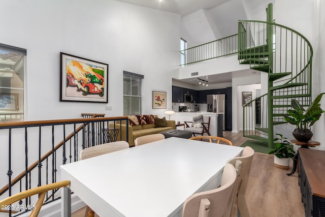 dining area with a towering ceiling and wood-type flooring