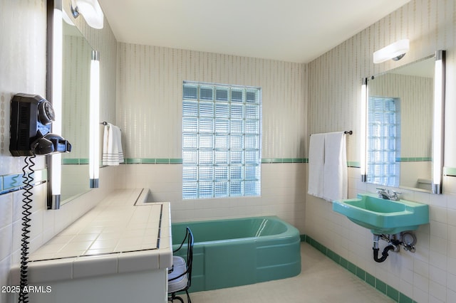 bathroom featuring a wealth of natural light, tile walls, and a bathing tub