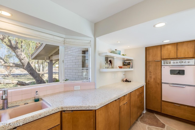 kitchen with light stone counters, sink, and double oven