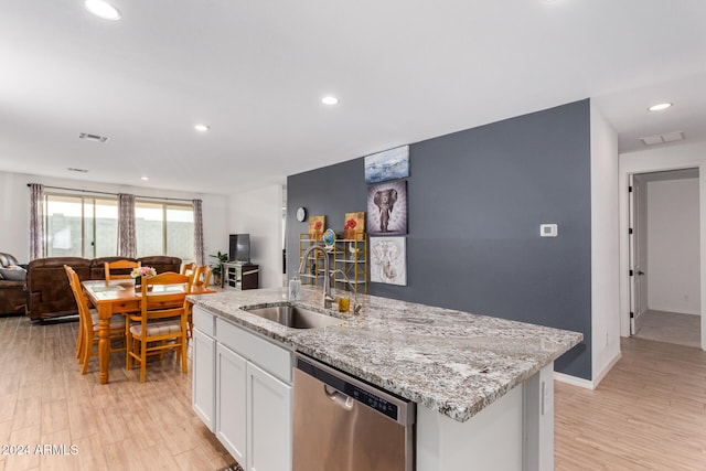 kitchen with white cabinets, light hardwood / wood-style flooring, stainless steel dishwasher, and a kitchen island with sink